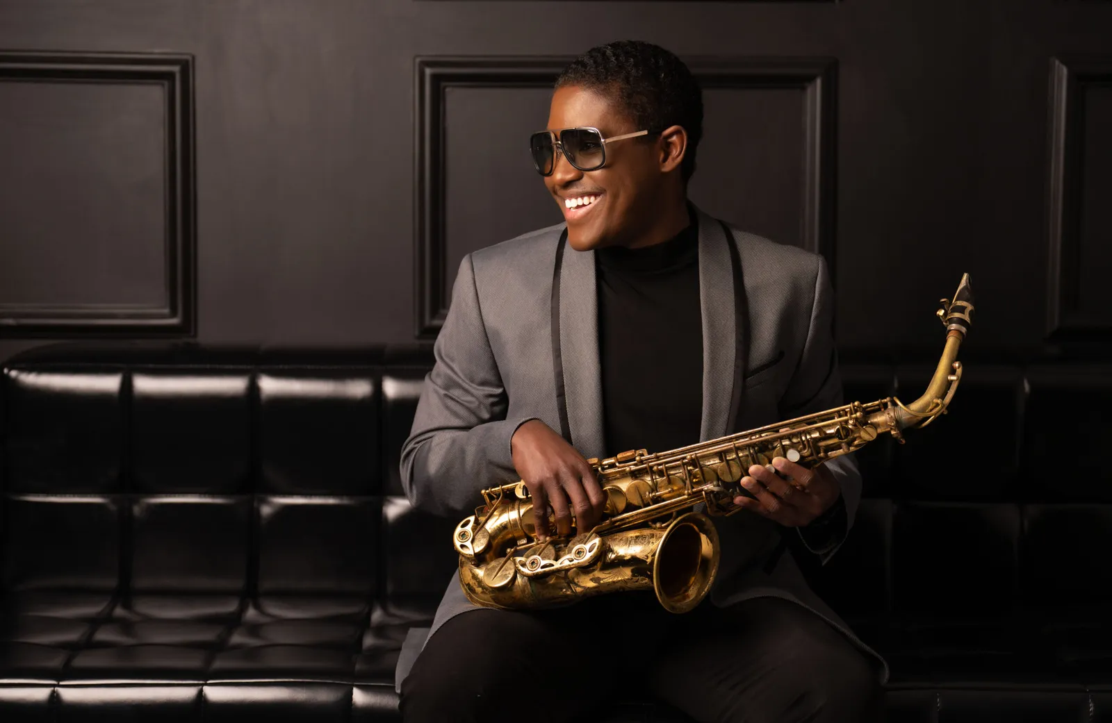 A saxophonist with a gold saxophone in a dark jazz club